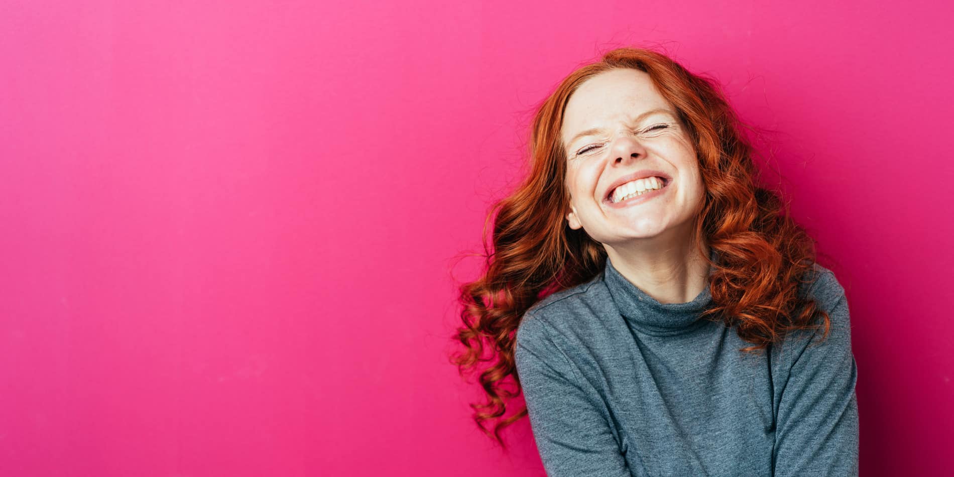 iStock-1084438582_women-_1900x950 Lachende Lady mit roten Haaren und rosa Hintergrund